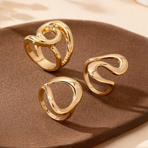 Detailed close-up of three irregular gold wave rings with a polished mirror finish