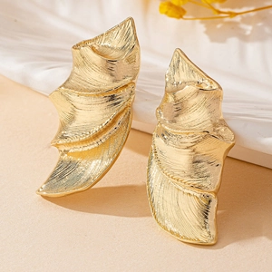 Vue macro détaillée des boucles d'oreilles feuilles dorées avec finition en métal brossé texturé