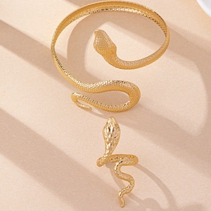 Detailed close-up of golden snake jewelry set with bracelet and ring on a beige podium