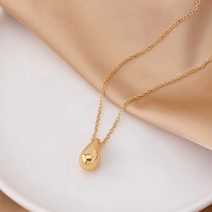 Eleganter goldener Tropfenanhänger auf Seidenstoff, minimalistische französische Kette