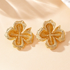 Detail of gold flower earrings with brushed texture and elegant four-petal design