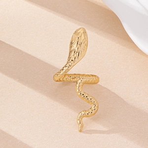 Close-up of golden snake ring with scales and star engravings on a beige pedestal