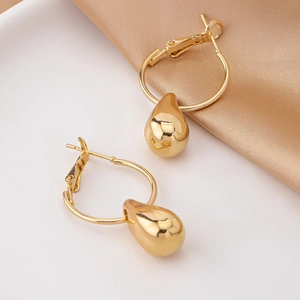 Elegant gold teardrop earrings with mirror polish finish on silk background
