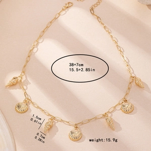 Collier doré style océan avec pendentifs coquillage et conque sur fond de sable
