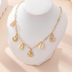 Collier élégant en chaîne dorée avec coquillages blancs et pétoncles dorés sur présentoir
