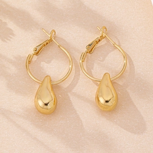 Macro shot of elegant gold teardrop earrings with high-polish finish on textured paper