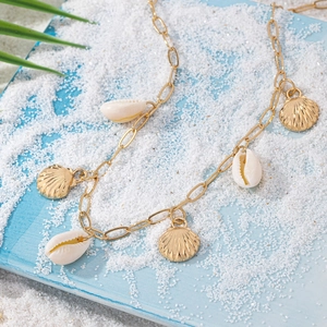 Collier coquillages dorés avec coquilles blanches naturelles sur sable blanc