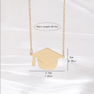 Golden graduation cap necklace with tassel pendant on elegant white silk background