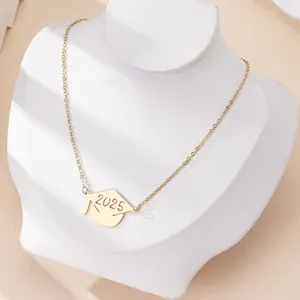 Golden 2025 graduation cap pendant necklace displayed on a minimalist jewelry bust