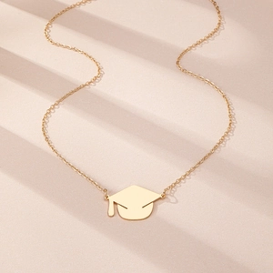 Detail of a polished gold graduation cap pendant necklace with elegant shadow lighting