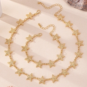 Gros plan détaillé d'un ensemble collier et bracelet étoile de mer en or mat sur sable