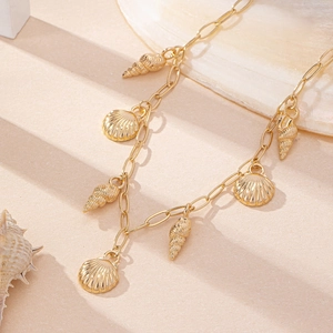Detail of golden ocean-style necklace with textured scallop shell and conch charms