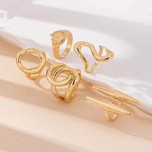 Detailed view of 5-piece gold alloy rings set on beige textured stone and ceramic dish