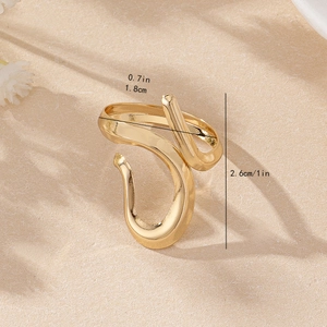 Irregular gold flowing line open ring on textured sand background with soft shadows