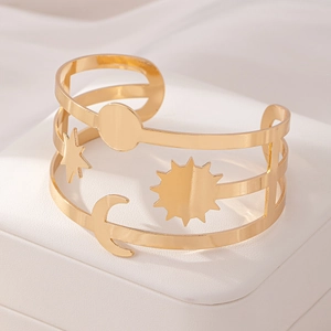 Close-up of golden hollow cuff bracelet with sun and moon celestial metal engravings