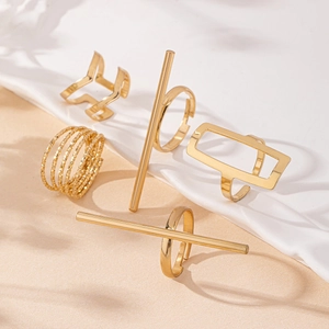 Macro shot of minimalist gold geometric rings five-piece set on silk with soft shadows