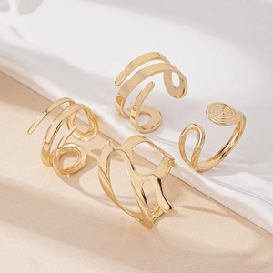 Detailed view of four irregular geometric gold rings with spiral and swirl textures
