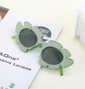 Detail of green leaf-shaped glitter sunglasses for party wear on a white magazine background