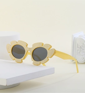 Close-up of yellow glitter cloud-shaped sunglasses on a minimalist stone display