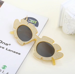 Macro shot of yellow glitter flower sunglasses with irregular frame and grey lenses