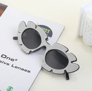 Close-up of irregular flower-shaped glitter sunglasses with round black lenses and silver frame