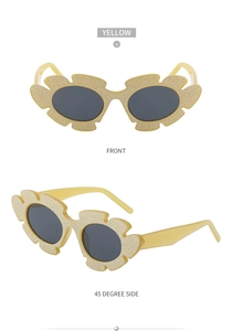 Detail view of yellow irregular flower sunglasses with gold glitter finish and grey lenses