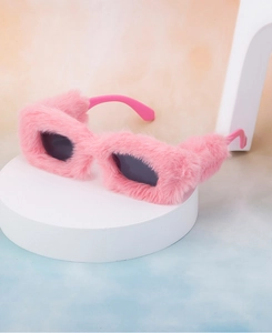Close-up of pink plush faux fur sunglasses on a platform with soft gradient background