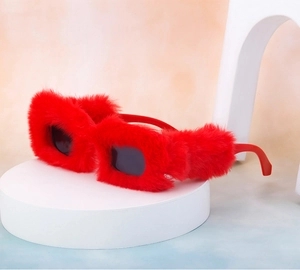Close-up of red plush fuzzy square sunglasses with soft texture on a white stand