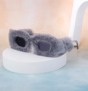 Close-up of square sunglasses with grey faux fur trim on a modern display stand