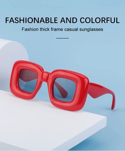 Detail of red square sunglasses with thick frames and dark lenses on a blue background