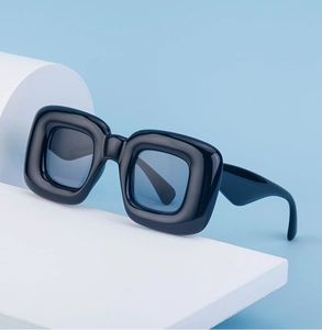 Detail of chunky black square frame sunglasses with light blue lenses on geometric stand