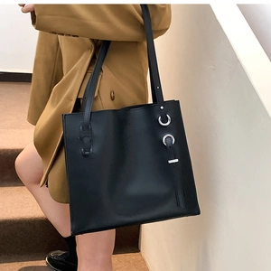 Detail of black leather tote bag with silver metal ring and wide shoulder straps