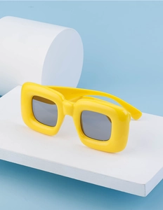 Detail of trendy yellow chunky square sunglasses on minimalist blue background