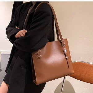 Detail of brown leather tote bag showing silver metal eyelets and decorative buckle