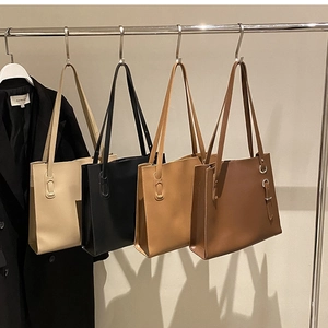Detail of four retro minimalist tote bags in cream, black, and brown hanging on a rack