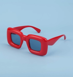 Detail view of bold red square sunglasses featuring chunky frames and blue lenses