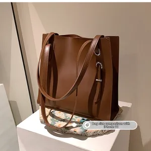 Brown leather tote bag size comparison with an iPhone 11 on a minimalist stone display