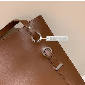 Detail of adjustable shoulder strap with silver buckle on brown vintage tote bag