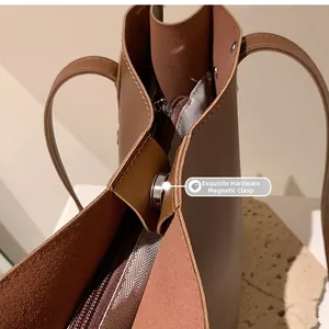 Detail of the magnetic buckle closure and herringbone lining on a brown leather tote bag