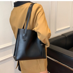 Close-up of a minimalist black leather tote bag in a stylish urban interior setting