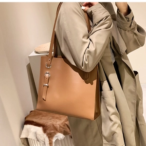 Detail of tan leather tote bag featuring a silver buckle and adjustable shoulder strap
