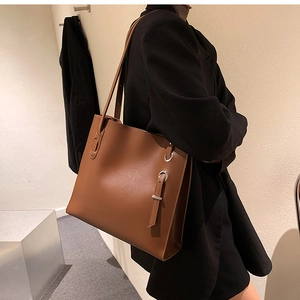 Brown leather tote bag with metal ring detail shown on model for a minimalist commute style