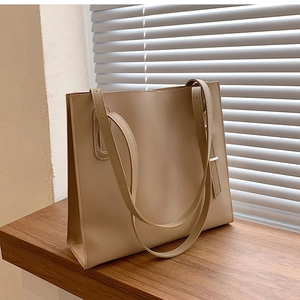 Detail of minimalist beige faux leather tote bag with adjustable shoulder straps