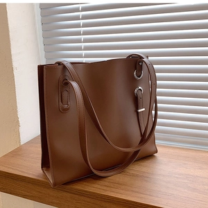 Detail of silver metal rings and adjustable straps on brown leather tote bag