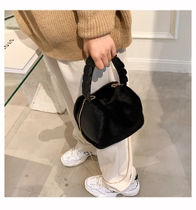Detail of black fluffy faux fur handbag with golden chain strap for women