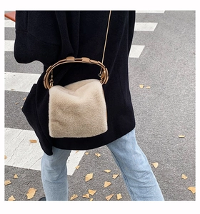 Detail of plush faux fur handbag with circular metal handle and detachable shoulder strap