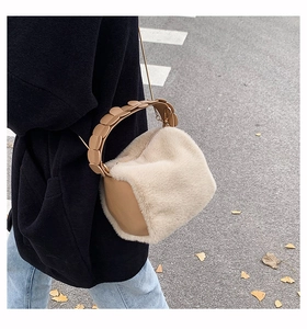 Detail of beige faux fur handbag with khaki leather accents and decorative handles