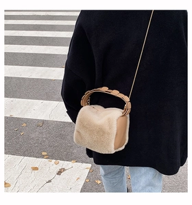 Detail of plush beige faux fur crossbody bag with gold chain and ring handle on model