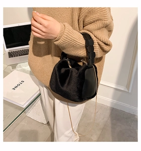 Detail of plush black handbag with faux fur texture, leather handle and gold chain strap