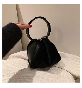 Detail of black triangular bag featuring plush faux fur panels and a round rigid handle
